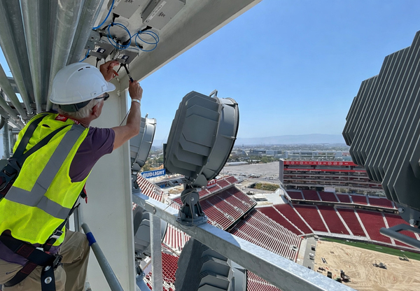 Mike Janssen, DGP Construction Manager, servicing DAS equipment installed near stadium lighting infrastructure located above the highest bowl seating sections in the venue